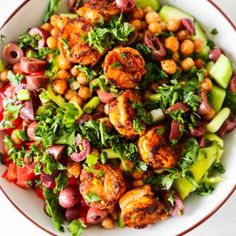 a white bowl filled with shrimp, chickpeas and avocado on top of a table