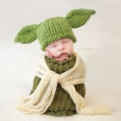 a newborn baby wearing a knitted green hat and scarf wrapped around it's face