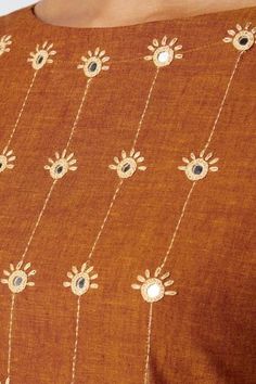 a close up of a woman wearing a brown top with flowers and chains on it