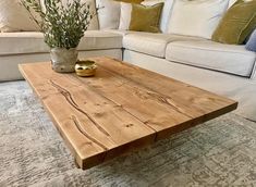 a wooden coffee table sitting on top of a carpeted floor next to a white couch