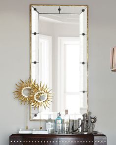 a mirror sitting on top of a wooden dresser next to a table with a lamp