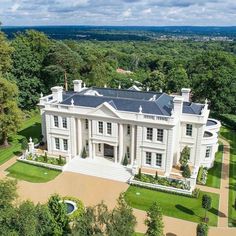 an aerial view of a large white house in the middle of some trees and grass