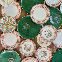 green and pink plates with floral designs on them are stacked next to each other in rows