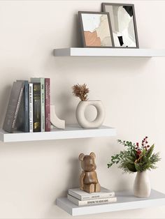 two white shelves with books and vases on them, one has a bear figurine