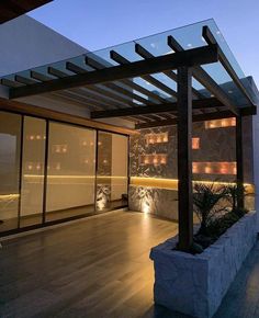 an outdoor living area with wood flooring and stone planters on the side of the building