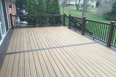 a wooden deck with metal railings in front of a house