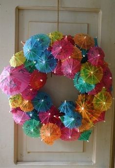 a wreath made out of umbrellas hanging from the side of a door with lights on it