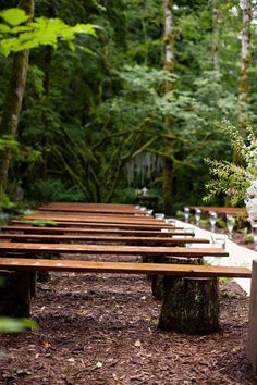 a bunch of wooden benches sitting in the middle of a forest with flowers on them