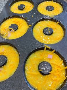 some food is being cooked in a muffin tin with cheese and black olives