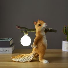 a figurine of a squirrel holding a branch in it's mouth on a table