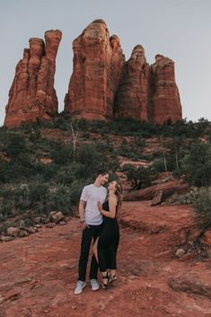 a man and woman standing in front of red rocks