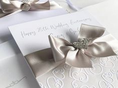 two wedding cards with silver bows on them