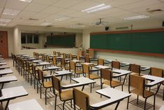 an empty classroom filled with desks and cars parked in front of the chalkboard