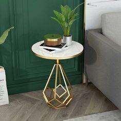 a small table with a potted plant on it next to a couch and green wall