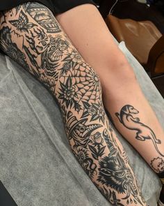 a person laying on top of a bed with tattoos on their arm and leg sleeves