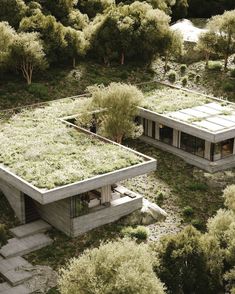 an aerial view of two concrete buildings with plants growing on the roof and trees in the background