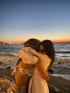 two women hugging each other on the beach