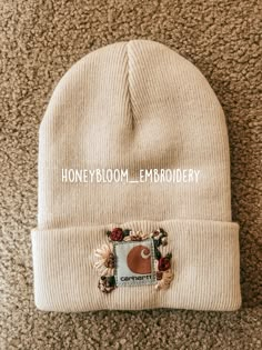 a white beanie with the words honeyboom embroidery on it sitting on a carpet