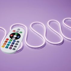 a remote control sitting on top of a purple surface next to white corded cords