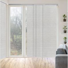 a living room with a couch and sliding glass doors that have white blinds on them