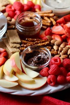 an assortment of fruits, nuts and dips on a platter with chocolate spread