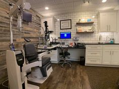 a dentist chair sitting in front of a desk with a computer monitor on top of it