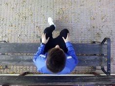 a person sitting on a bench with their feet up in the air and one hand over his head