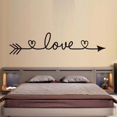 a bedroom with a bed, nightstand and wall sticker that says love on it