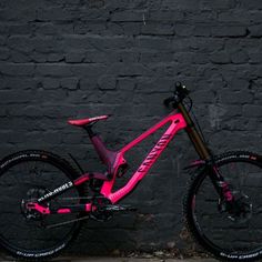 a pink and black bike leaning against a brick wall in front of a dark background