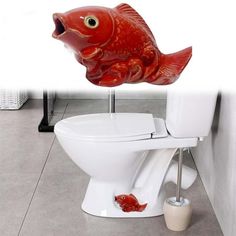 a toilet with a red fish on it's tank and the lid up in the air