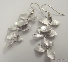 These silver orchid earrings are so sophisticated, delicate and simply stunning. They are perfect for any occasion and they make a wonderful bridal gift - for the bride or the bridesmaids! These earrings feature three lightweight, cascading matte silver plated orchids. They are finished off with stainless steel ear wires, for those with sensitive ears. The ear wires can be switched out to silver plated clip-ons, for those with non-pierced lobes. Simply select that option before adding to your ca Hypoallergenic Sterling Silver Flower Earrings For Wedding, Elegant Orchid Flower Earrings, Dainty Silver Flower Earrings For Wedding, Delicate Silver Earrings For Bridesmaid Gift, Silver Flower Drop Earrings For Bridesmaid Gift, Dainty Silver Bridal Earrings For Bridesmaid Gift, Silver Dainty Bridal Earrings For Bridesmaid Gift, Delicate Silver Flower Earrings For Wedding, Delicate Hypoallergenic Flower Earrings For Wedding