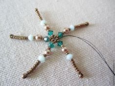 a beaded star ornament is shown on a piece of fabric with beads