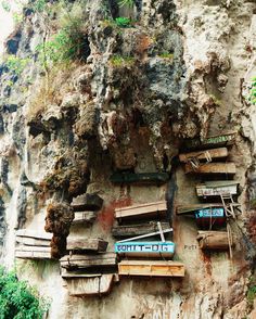 an old wall with wooden benches and graffiti written on the side, near a cliff