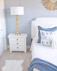 a bedroom with a white bed, blue and gold decor and a mirror on the wall