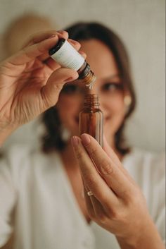 a woman holding an essential oil bottle in front of her face