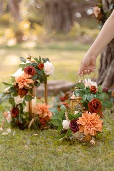 a person placing flowers on top of a wooden box with candles in the grass next to it