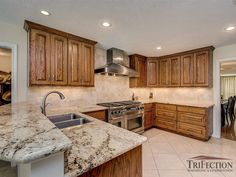 a kitchen with marble counter tops and wooden cabinets