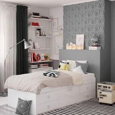 a white bed sitting in a bedroom next to a black and white striped rug on top of a hard wood floor