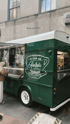 a green food truck parked in front of a building