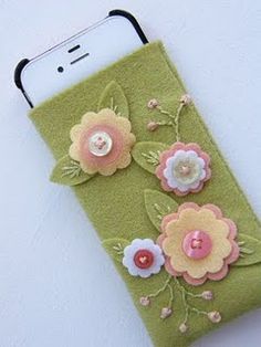 a cell phone case with flowers and buttons on the front, sitting on a table