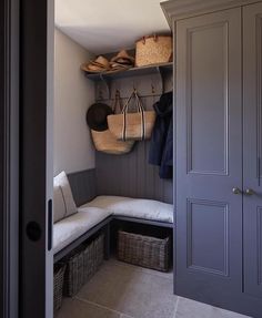 an entryway with baskets and coats hanging on the wall, along with a bench