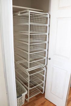 a white closet with baskets on the bottom shelf and an open door to another room