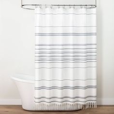 a white bath tub sitting next to a shower curtain with black and white stripes on it