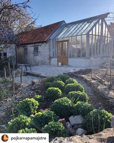 an old house with a glass roof and garden in the foreground, surrounded by rocks