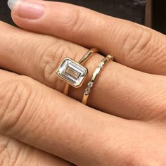 a woman's hand with two gold rings and an engagement ring on her finger