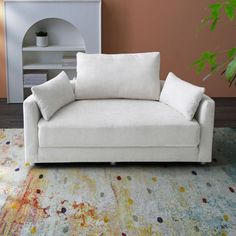 a white couch sitting on top of a colorful rug