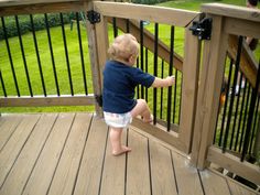 a little boy standing on top of a wooden deck next to a fenced in area