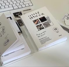 an open book sitting on top of a white desk next to a keyboard and mouse