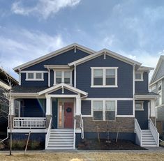 a blue two story house with white trim on the front porch and stairs leading up to the second floor