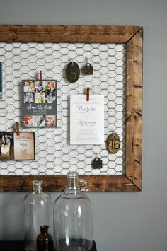 a wooden frame with magnets and pictures on the wall next to two glass jars